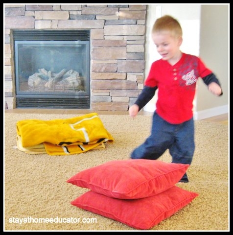 Toddler running around pillows and leaping like a frog