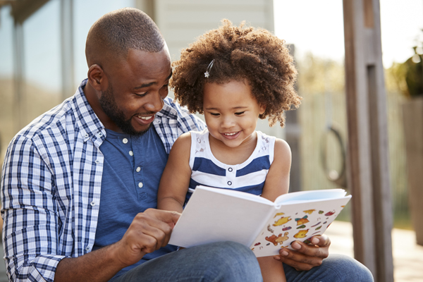 stages of reading developing, father and daughter reading books together in literacy rich environment in the home