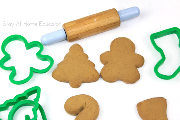 edible gingerbread playdough recipe |  gingerbread scented playdough cut out with cookie cutters, a gingerbread man, Christmas tree, stocking and candy cane, and playdough tool rolling pin