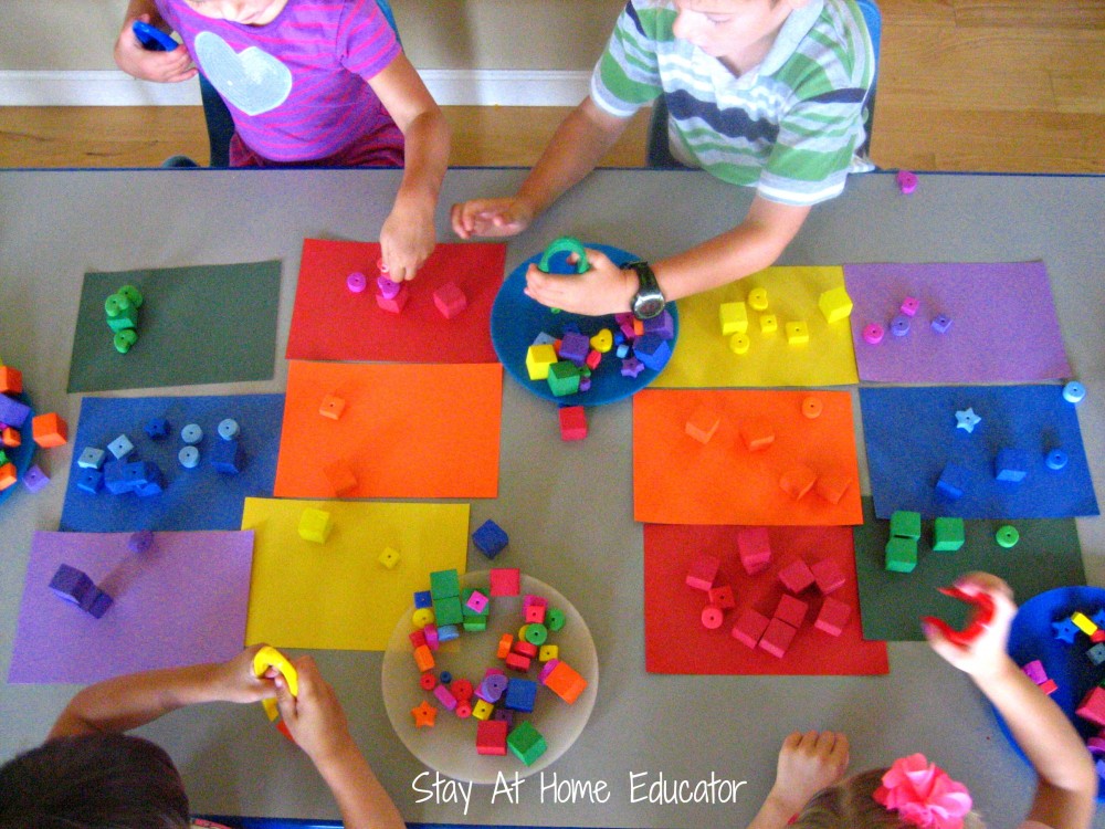 Using jumbo tweezers to work on fine motor development by sorting foam items by color - Stay At Home Educator