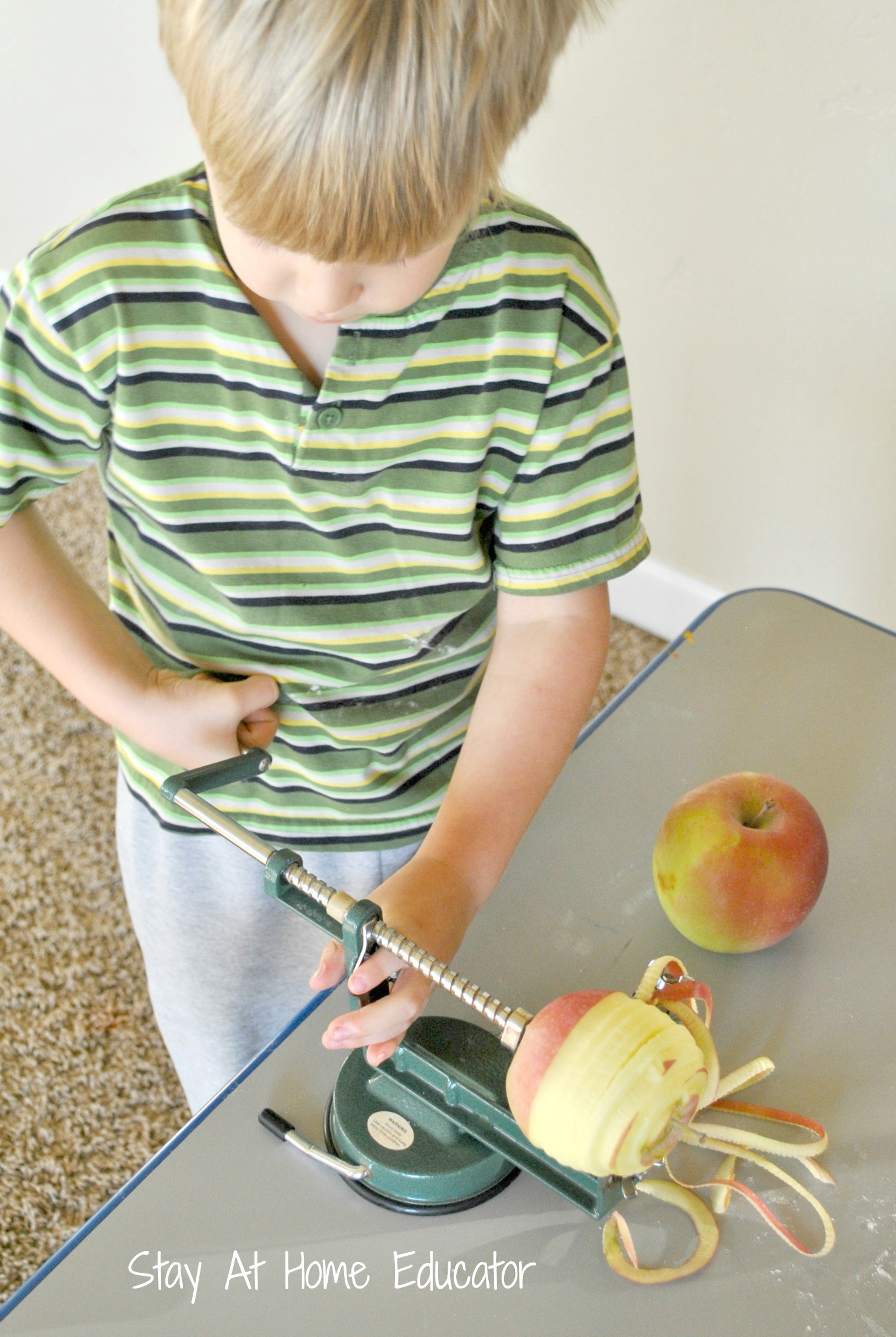 Preschooler cranking apple peeler to help make mini apple pies - Stay At Home Educator