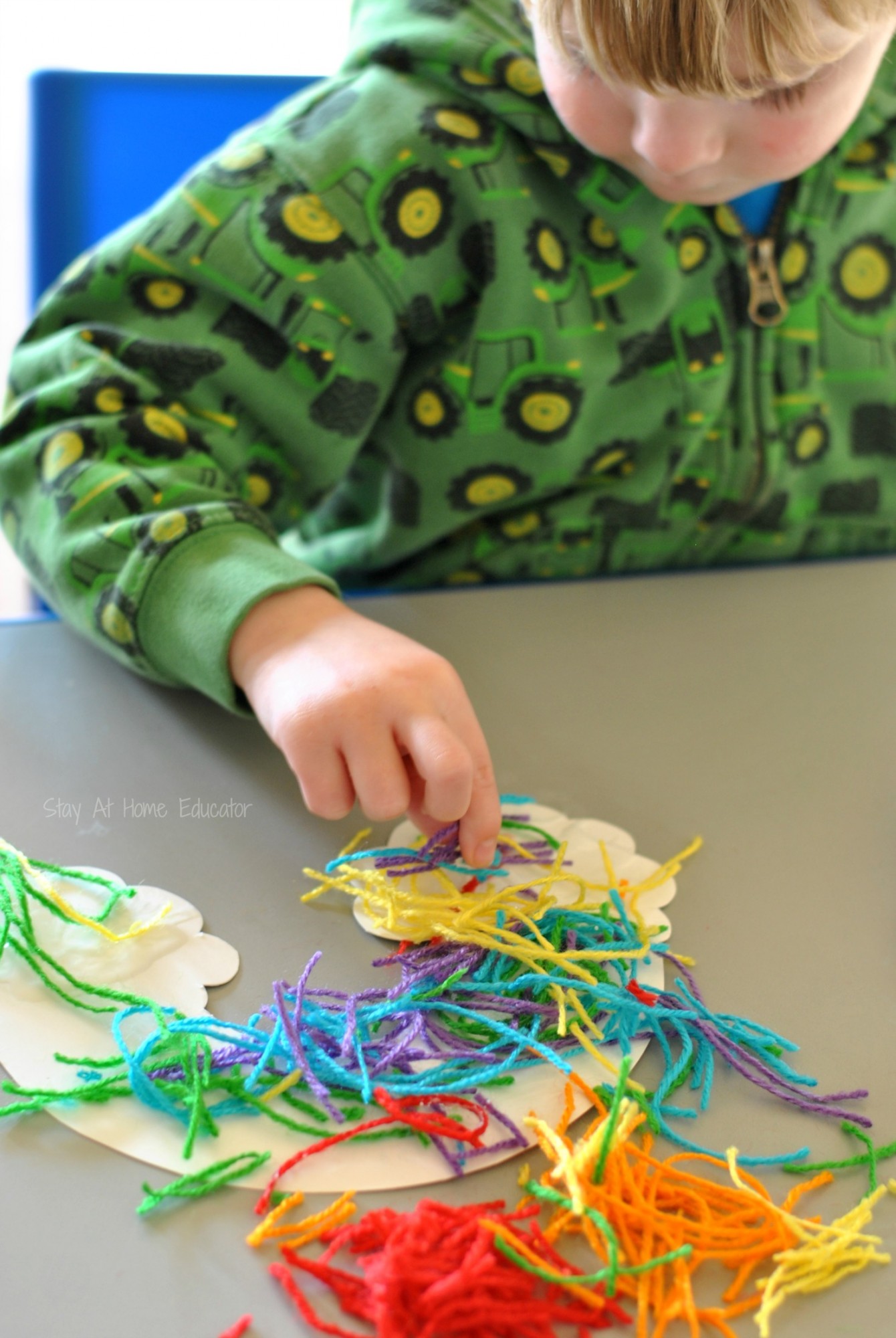 Yarn rainbow craft for three year olds - Snipped yarn rainbows, a fine motor craft for preschoolers  - work on hand strength, fine motor skills, and scissor cutting practice while doing a rainbow craft for preschoolers. Add it to your st. Patrick's Day lesson plans