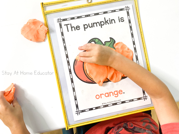 a child smooshes orange playdough to cover the orange page of the pumpkin colors booklet