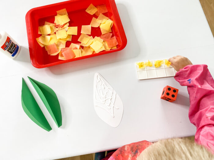 a child making a corn craft for a Thanksgiving preschool theme