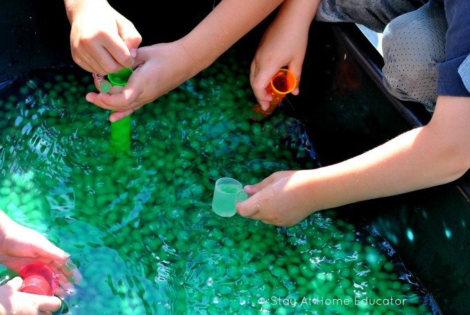 scooping and pouring practice with a water bead sensory bin in the summer time