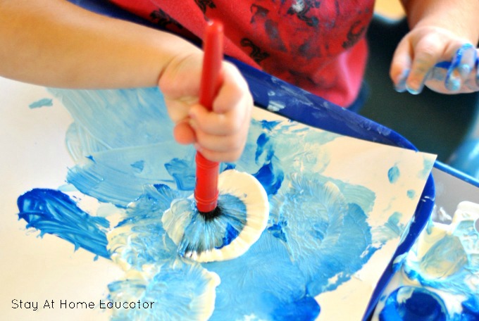 Sand, tissue paper, blue paint and star cut-outs to make ocean art, a process art in preschool