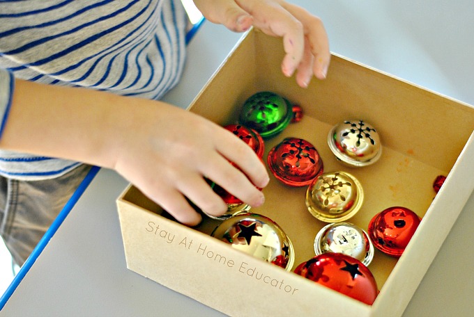 Christmas gift wrapping center for fine motor practice | Christmas fine motor gift wrapping center | preschoolers putting jingle bells into a box to be wrapped 