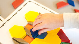 child placing blue rhombus on heart pattern block mat | valentine's math activities | Valentine's Day math | free pattern block mats |