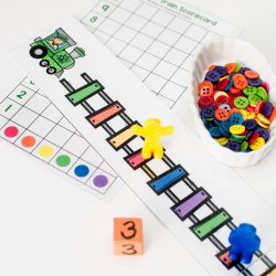 rainbow train tracks laid out with a yellow piece on the red track with a small bowl of rainbow buttons and a dice | rainbow preschool activities | counting activities for preschool |