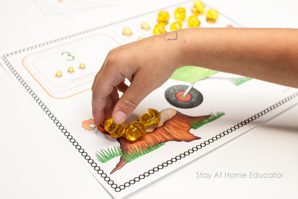 Sneaky Squirrel Fall Counting Activity | fall printables for preschoolers | sneaky squirrel ten frame | frame has image of ten acorns in frames with counters on top| the number 7 with acorns underneath | a tree stump with a brown squirrel | a green wheelbarrow | the words "sneaky squirrel and other FREE fall printables” written as the title| an image of a card with the numeral 5 and 5 acorns is at the very top |