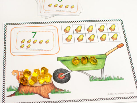 Sneaky Squirrel Fall Counting Activity| fall printables for preschoolers| sneaky squirrel ten frame| frame has image of ten acorns in frames with counters on top| the number 7 with acorns underneath| a tree stump with a brown squirrel| a green wheelbarrow|