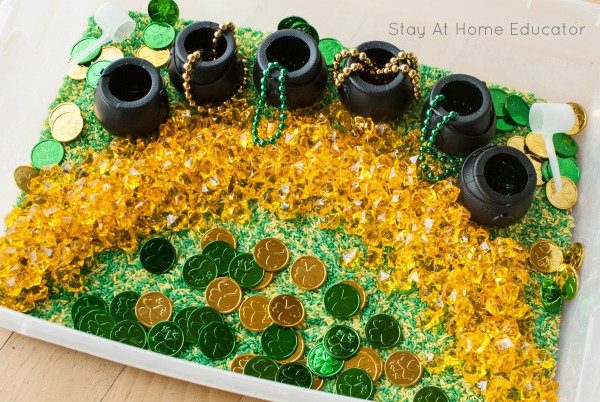 St. Patrick's Day sensory bin for preschool with rice, gold and green coins, yellow gem,s and black pots