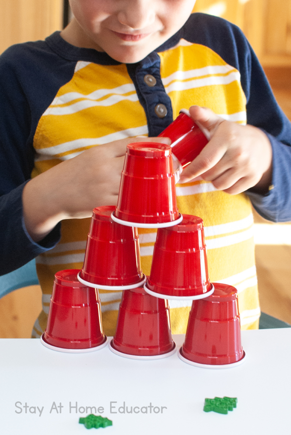 A preschooler has engineered a pyramid out of cups during his invitation to play