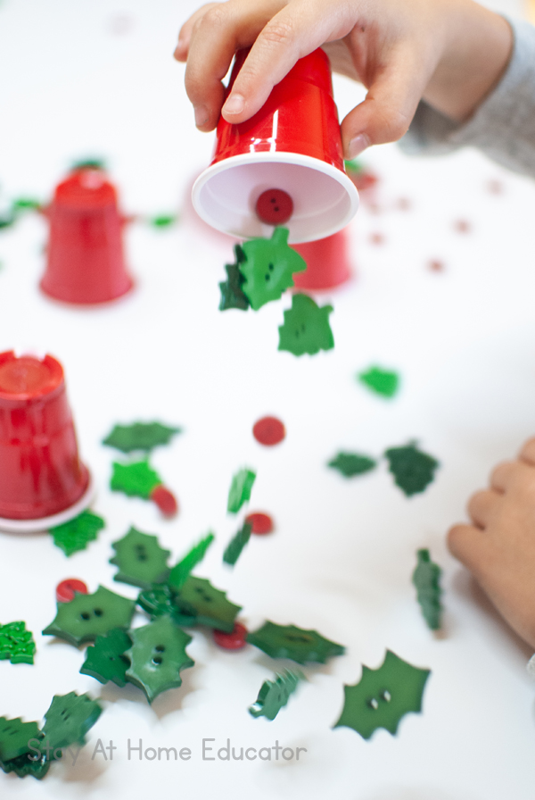 Buttons bounce across the table as a preschooler participates in a Christmas STEM activity