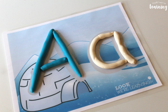 alphabet playdough mats| playdough letter mats with uppercase and lowercase letters and a picture| Uppercase letter A formed on letter mat A in blue playdough| lowercase letter a formed on letter mat a in white playdough| a white igloo image and blue and white snowy and mountainous scene, representing "A for Arctic".