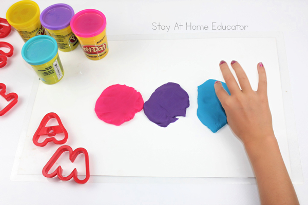 preschool name recognition activity using playdough | how to teach name spelling with playdough | playdough names | writing name practice | name recognition activity for preschoolers using playdough | child using three colors of playdough to cut out the letters in her name