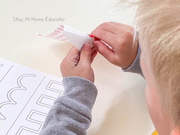 pre writing activities | prewriting worksheets | prewriting strokes | activities to teach preschool writing | preschool fall theme | fall leaves preschool activities | toddler using small sticker to place on tracing lines