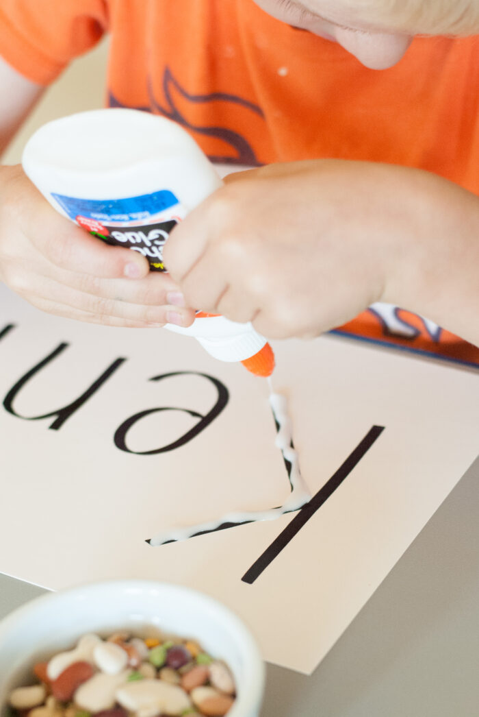 a boy works his fine motor skills by squeezing a glue bottle onto his seed activity