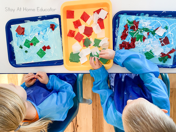 two preschool boys crumpling tissue paper squares to add to their Christmas art collage