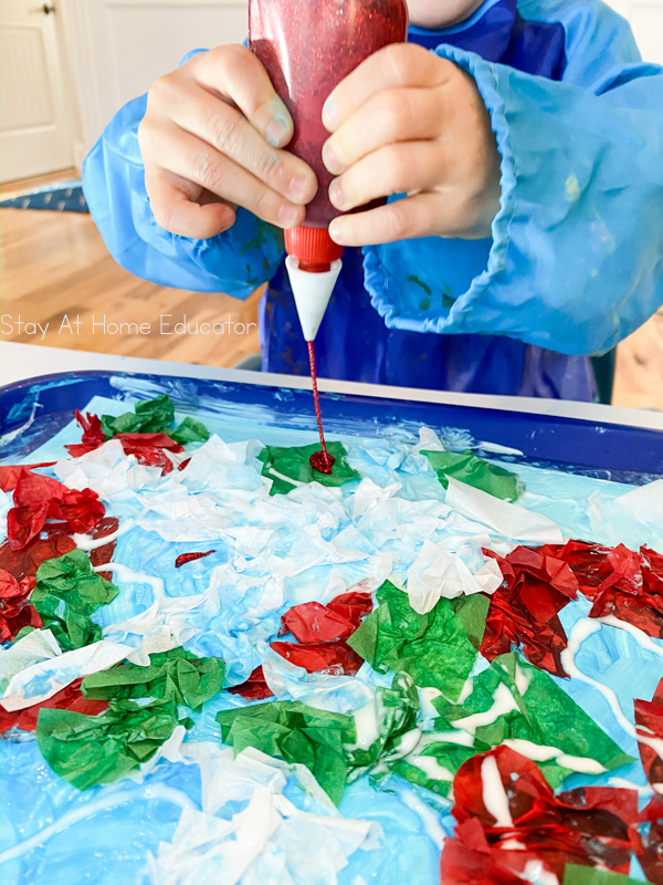 red glitter glue being squeezed on top of a Christmas art project for preschoolers