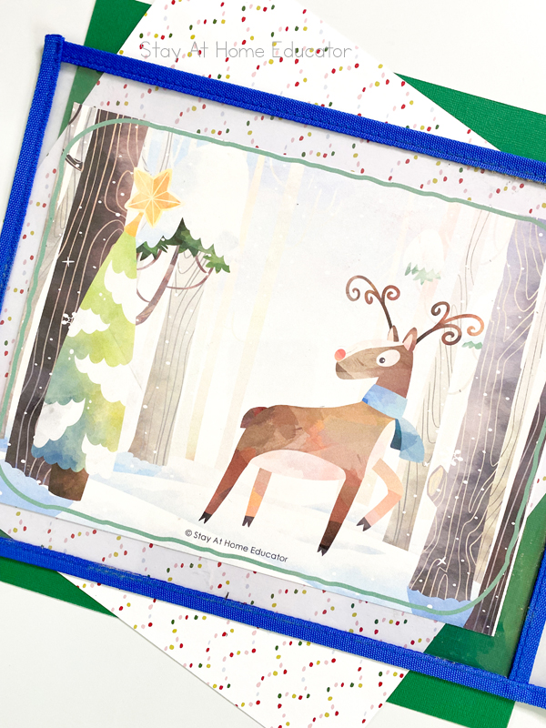 a free printable Christmas playdough mat featuring a reindeer and a tree is in a dry erase pouch