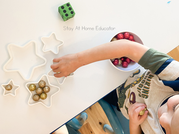 a smiling boy has added six balls to a cookie cutter as part of a Christmas themed math activity