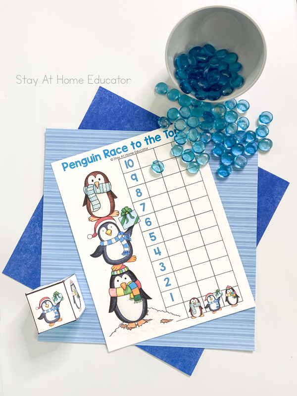 a die, penguin printable, and blue counters set out to teach simple graphs for preschoolers