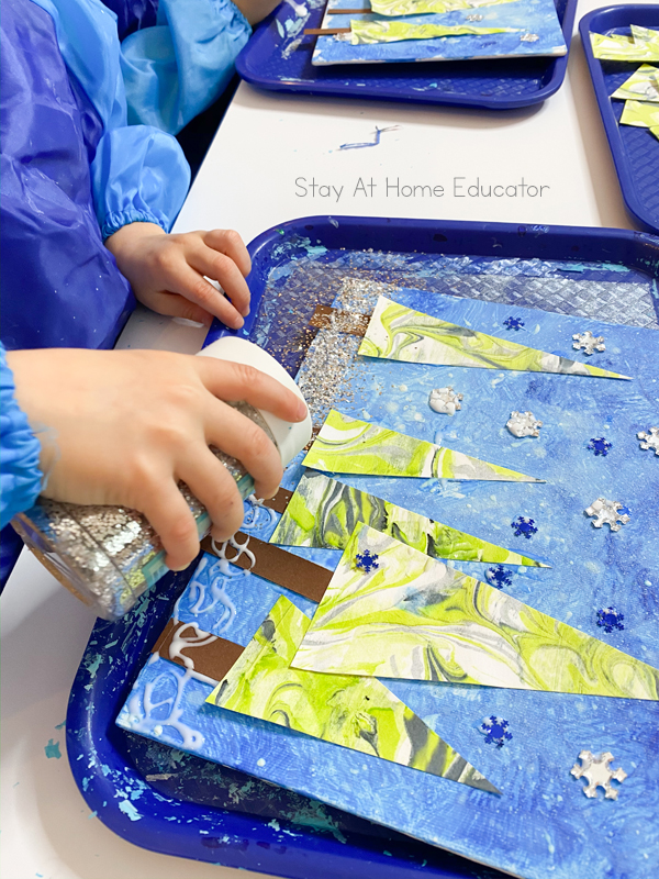 small hands adding glitter to their glittery winter art for preschool 