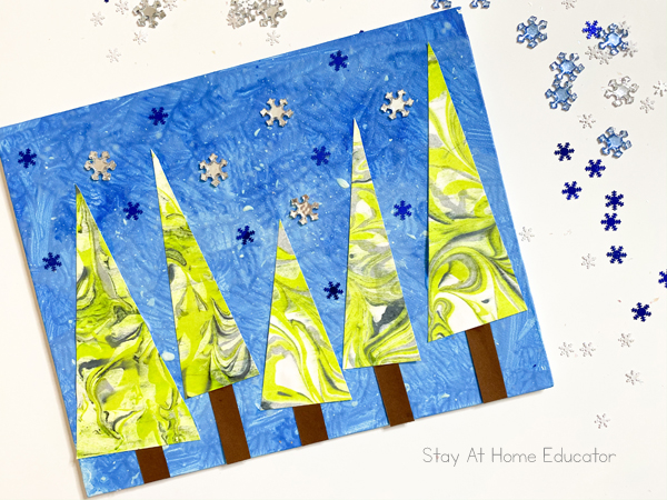 a finished landscape winter art project with marbled trees and snowflakes.