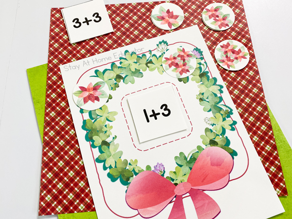 a preschool addition mat in the shape of a Christmas wreath with the addition sentence 1+3 in the middle and corresponding flower cards