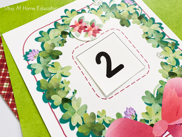 a preschool math activity for Christmas that is a printable wreath with the number two in it and a card showing two poinsettias