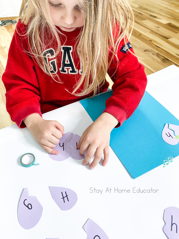 a child tapes an uppercase H to a lowercase h during a valentine's learning activity
