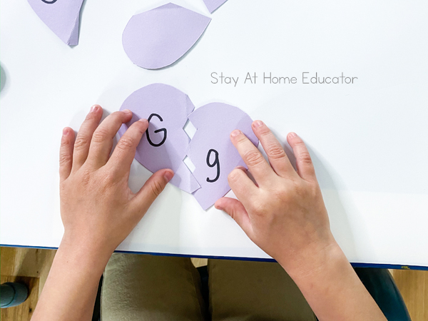 a child's hands complete a puzzle with the letter Gg as part of alphabet learning activities