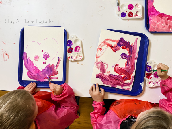 two preschool children using tempera paint on a piece of white cardstock