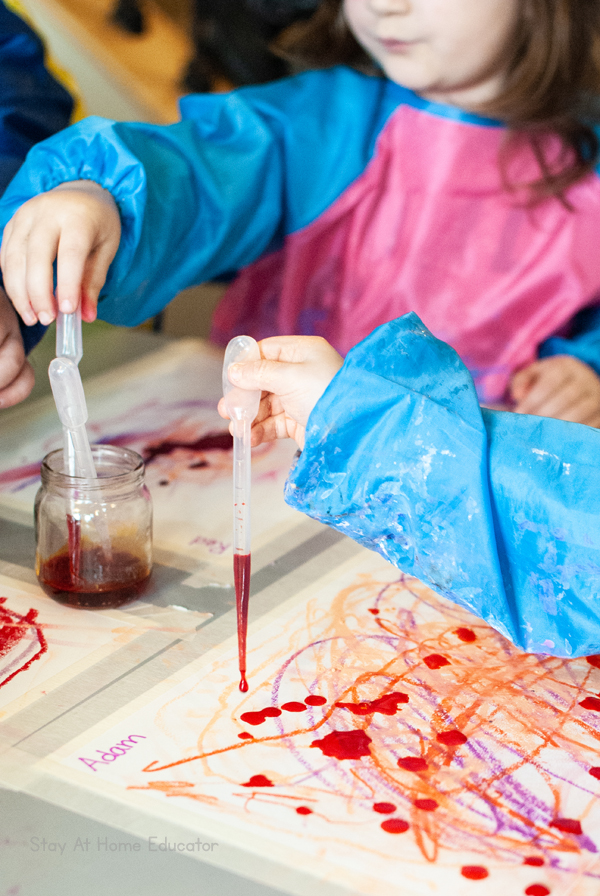 children drawing liquid watercolor into pipettes so they can put it on their valentine's day art project for toddlers