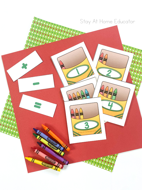 back to school math activities| math activities for back to school| preschool hands-on math activities| Pictures of four cards which have crayon box image each with a numeral, 1, 2, 3, 4 and each with its respective number of crayons showing in the box| miscellaneous real crayons| three small cards cut out, one with a plus sign, one with a minus, and one with an equals sign for addition and subtraction practice 