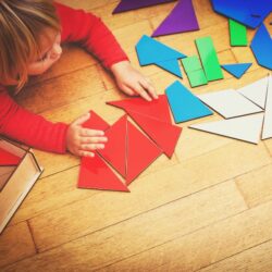 Children are using tangrams and pattern blocks to learn about shapes in the shapes lesson plans for preschool daily mathematics curriculum.