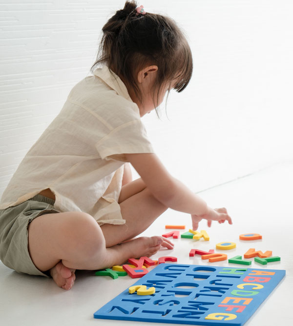 the hard facts about the importance of letter recognition in preschool, how to teach letter recognition, explicit and systematic phonics instruction in preschool - child putting together an alphabet puzzle