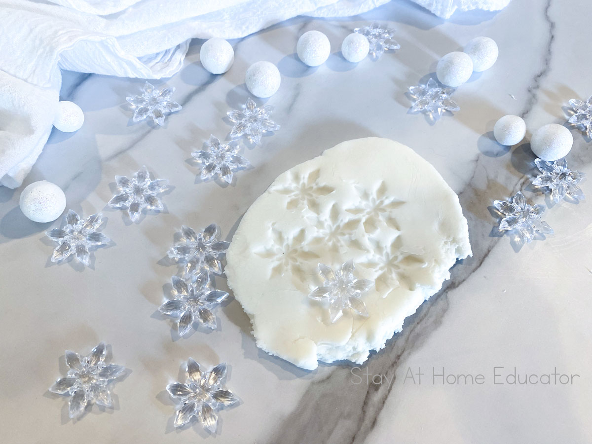 how to make white playdough | white playdough recipe without cream of tartar | ball of white playdough on parchment paper | winter playdough recipe with snowflake impressions