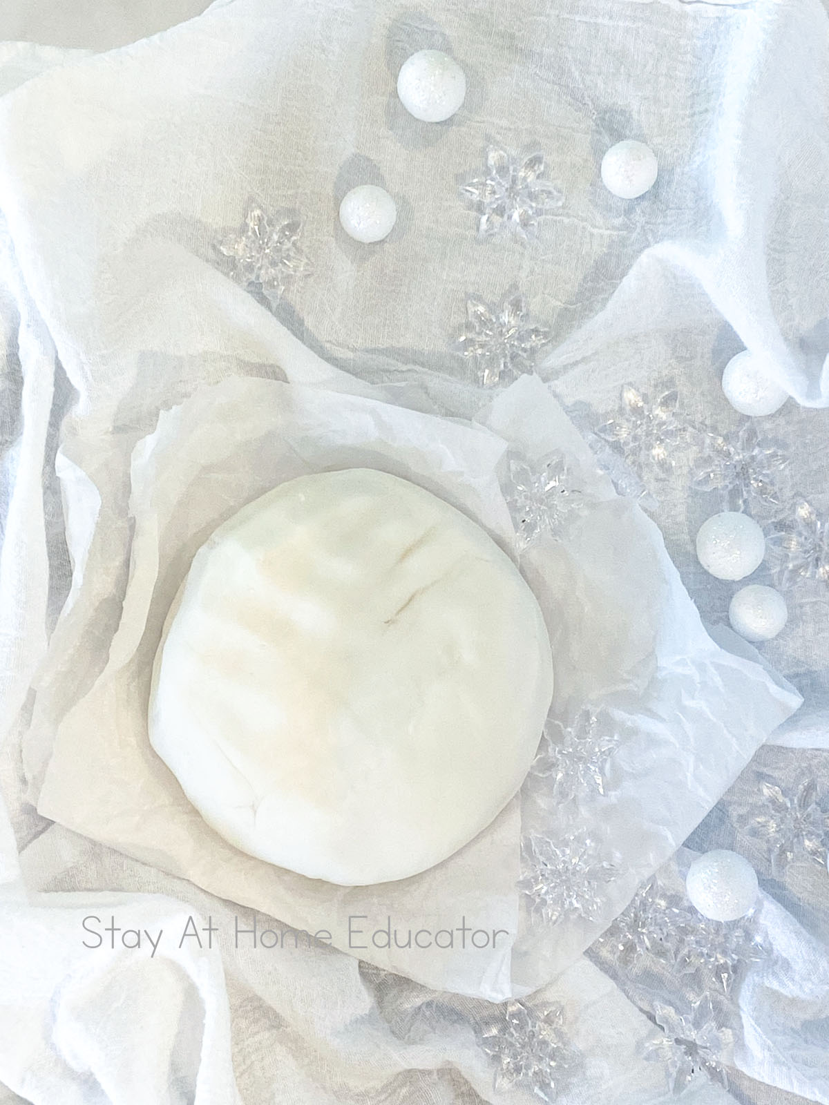 how to make white playdough | white playdough recipe without cream of tartar | ball of white playdough on parchment paper | winter playdough recipe with snowflakes and foam balls