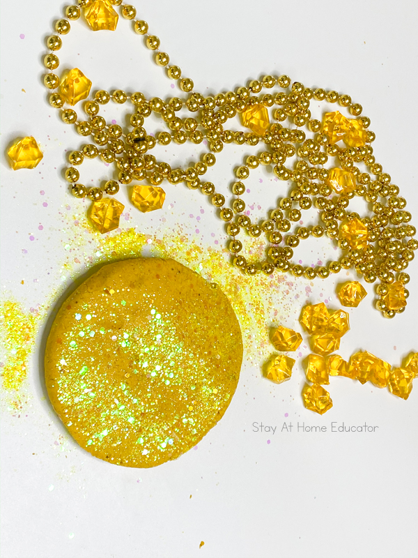 Shimmery gold playdough reflecting in the light, spilled glitter to make gold playdough, playdough pancake with yellow acrylic nuggets to look like gold for pirate preschool lesson plans