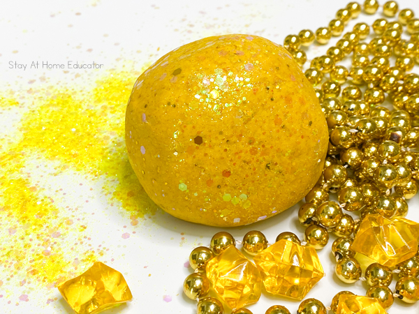 Shimmery gold playdough for pirate preschool theme or St. Patrick's Day theme | super soft playdough recipe for developing hand strength in preschoolers | ball of shimmery gold playdough with chunky glitter, gold nuggets and gold necklace pirate's booty