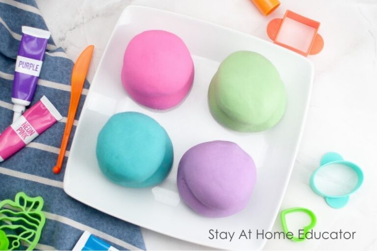 easiest ever playdough recipe super soft | fun and easy activity | four playdough in one white plate : color neon - pink, classic blue, purple, green with gel food coloring, cookie cutters and playdough tools | super easy, no-cook easy playdough recipe! | soft, colorful, and endlessly moldable
