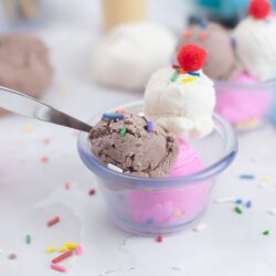 A colorful picture of a sundae dish filled with ice cream playdough that looks just like real Neapolitan flavors, with layers of chocolate, vanilla, and strawberry. This playful playdough recipe, which looks and scoops like real ice cream, is a fun and educational activity, great for teaching preschoolers about ice cream.